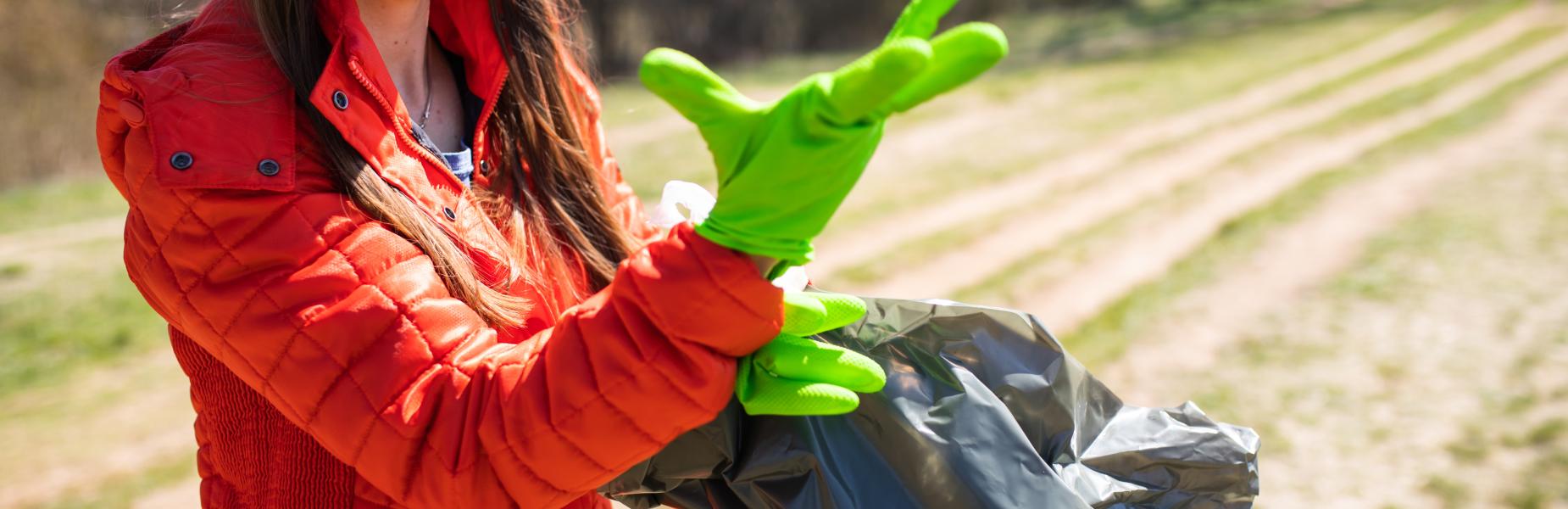 A woman wearing rubber gloves collecting rubbish