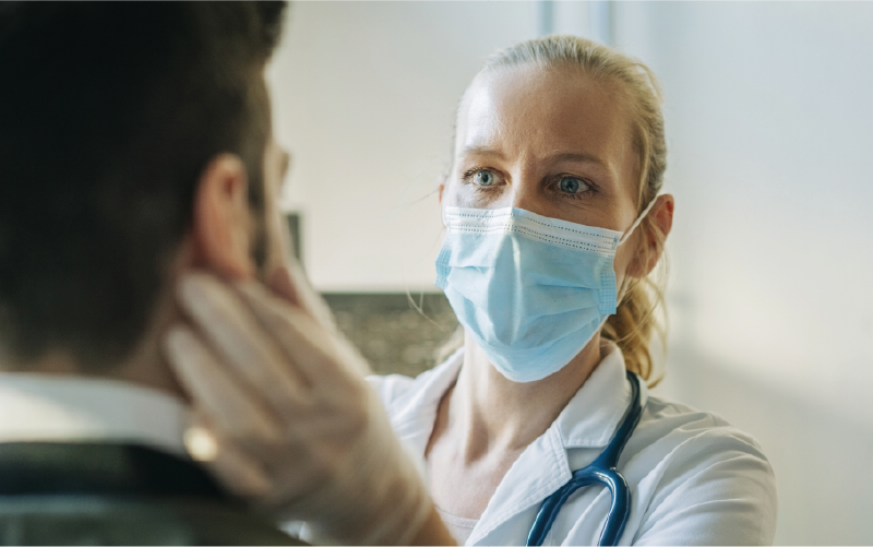 Photograph of doctor in face mask examining a patient