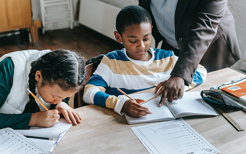 A teacher helping students with their work in their exercise books