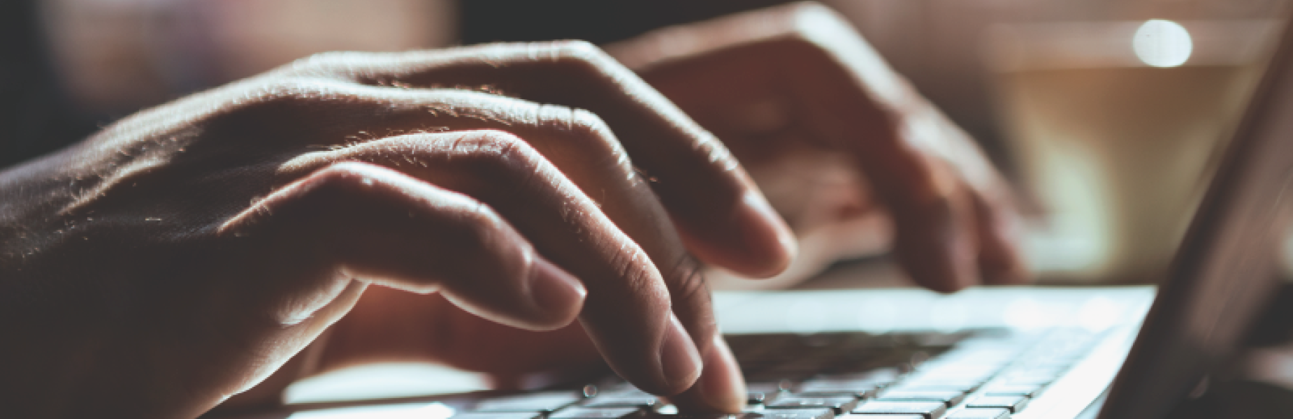 Hands typing a laptop keyboard