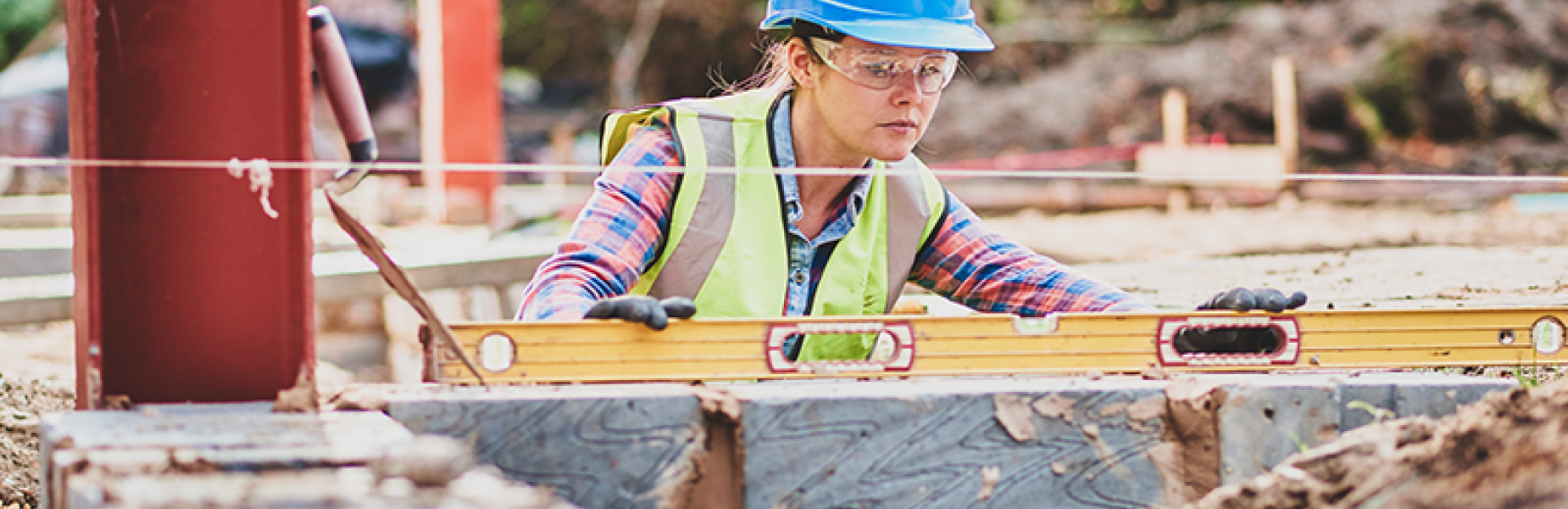 A young female builder using a level to build and check a wall