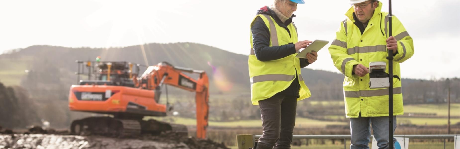 worksite with two people in high vis jackets and a digger