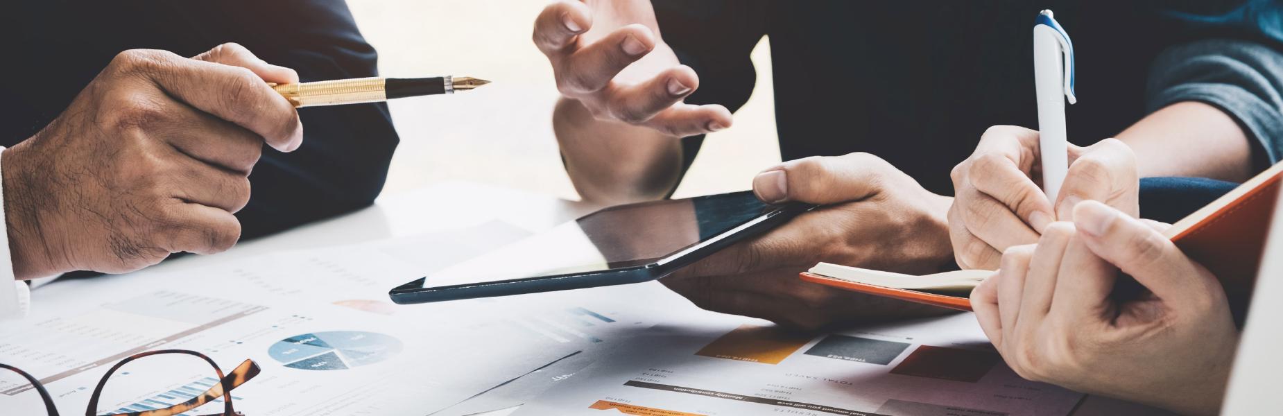 Three business people busy with documents discussing financial matters during a meeting
