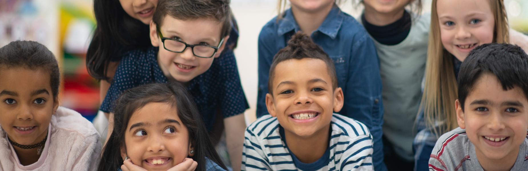 A group of children together in a classroom setting, looking towards the camera.